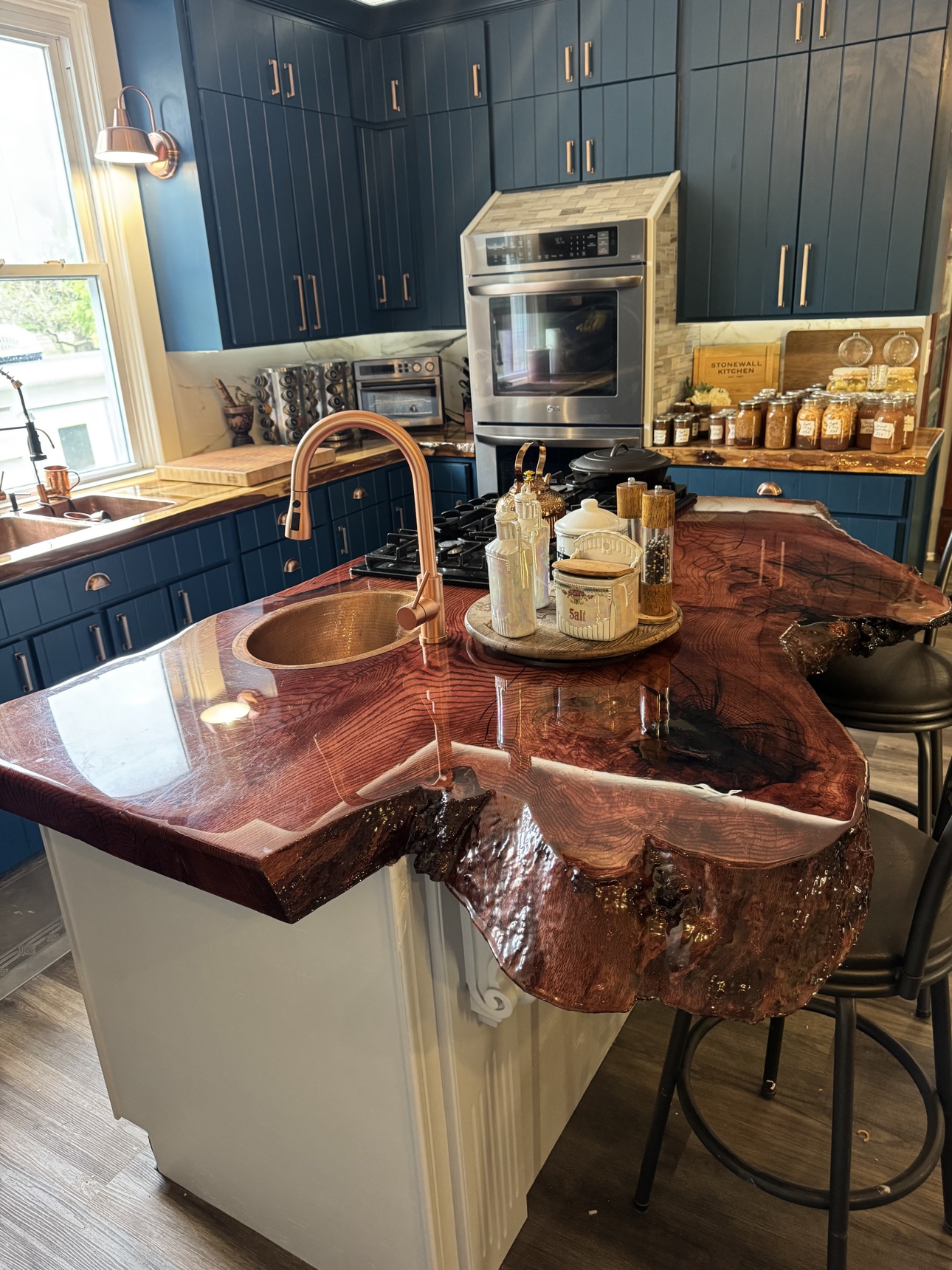 Kitchen island with live-edge countertop, copper sink, and navy base cabinets