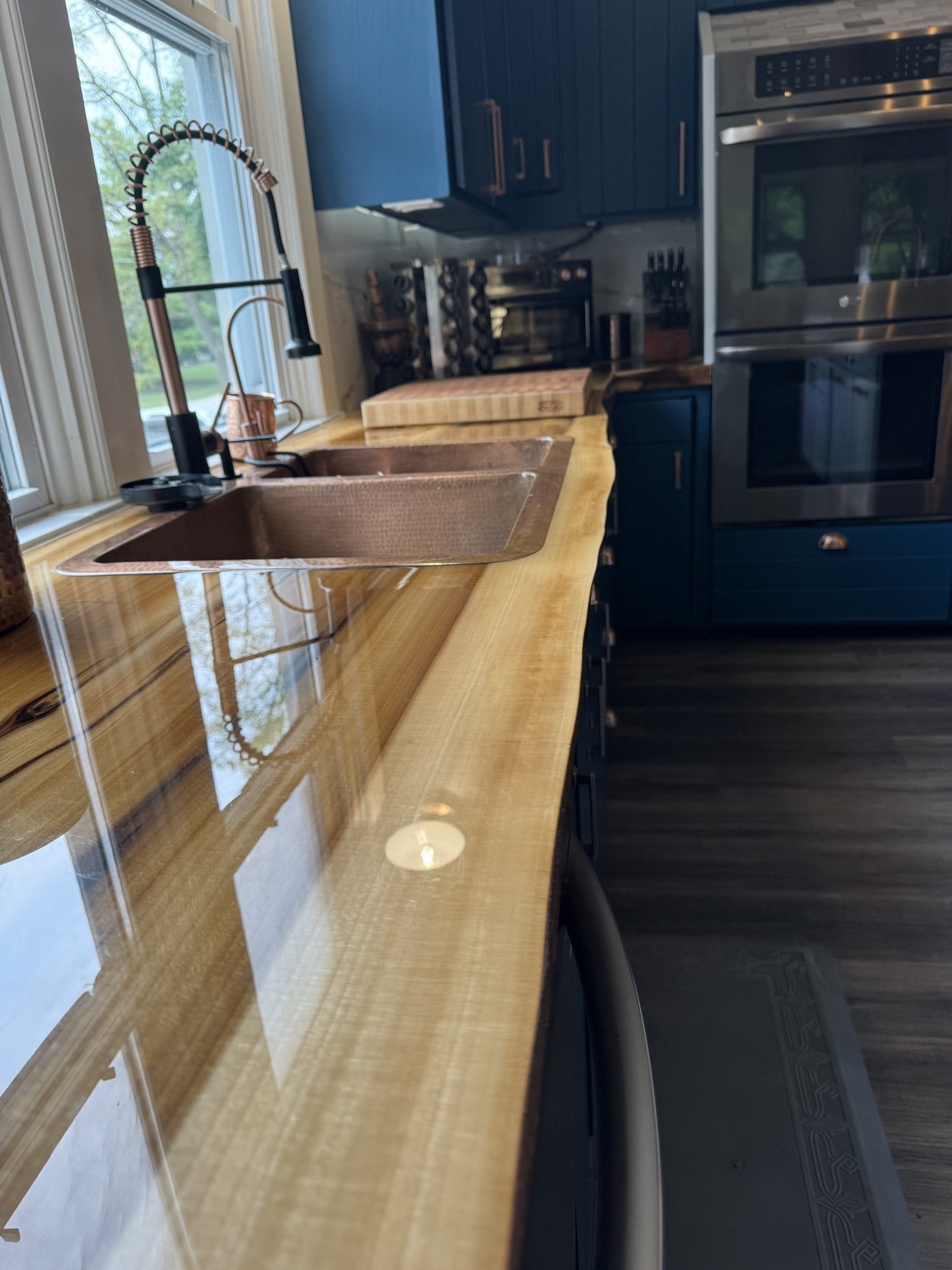 Hammered copper sink set into a live-edge wood countertop in a remodeled kitchen