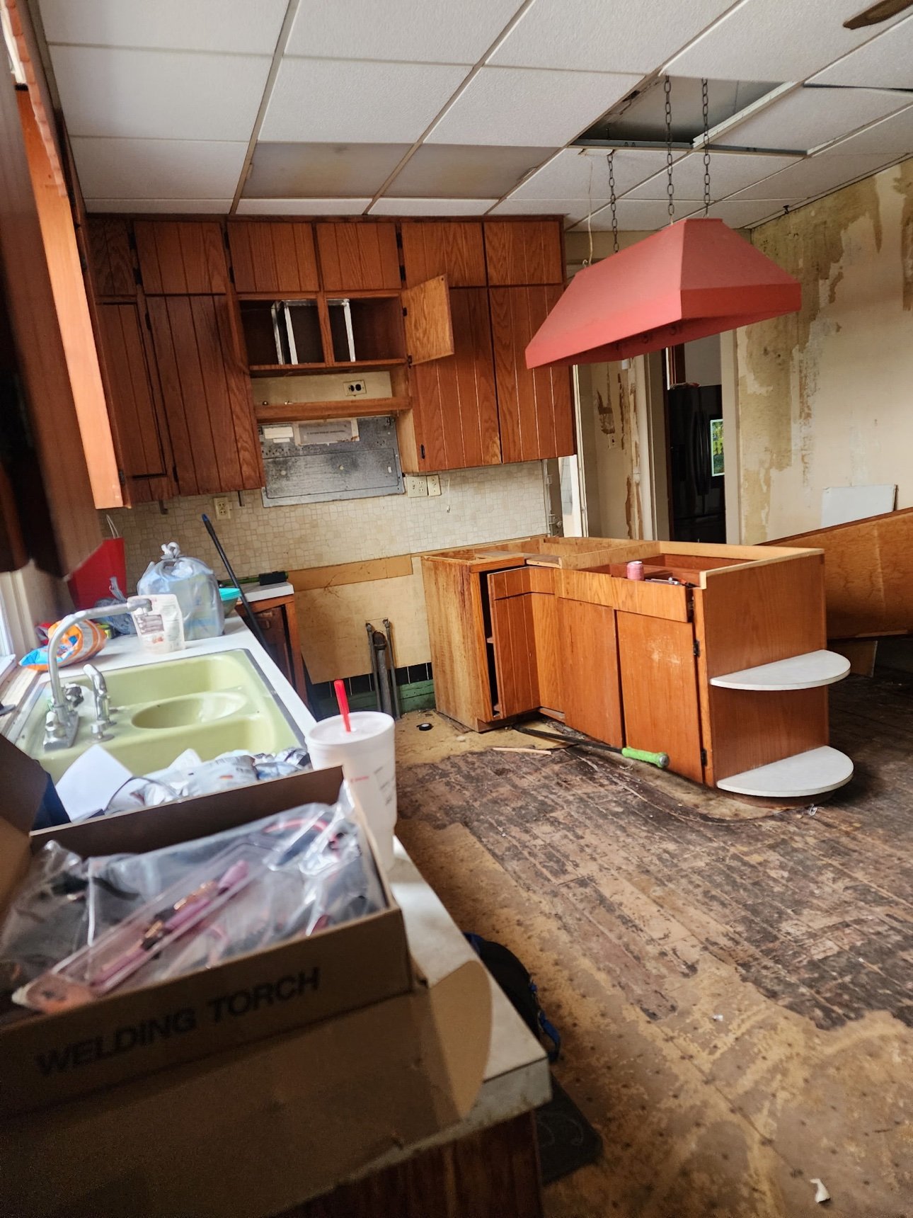 Victorian kitchen in Indianapolis before a full remodel — dated wood cabinets, drop ceiling, and a green sink