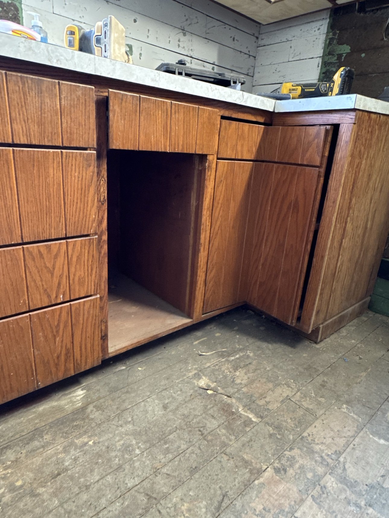 Original wood kitchen cabinets before remodeling — close-up of worn cabinetry and floors