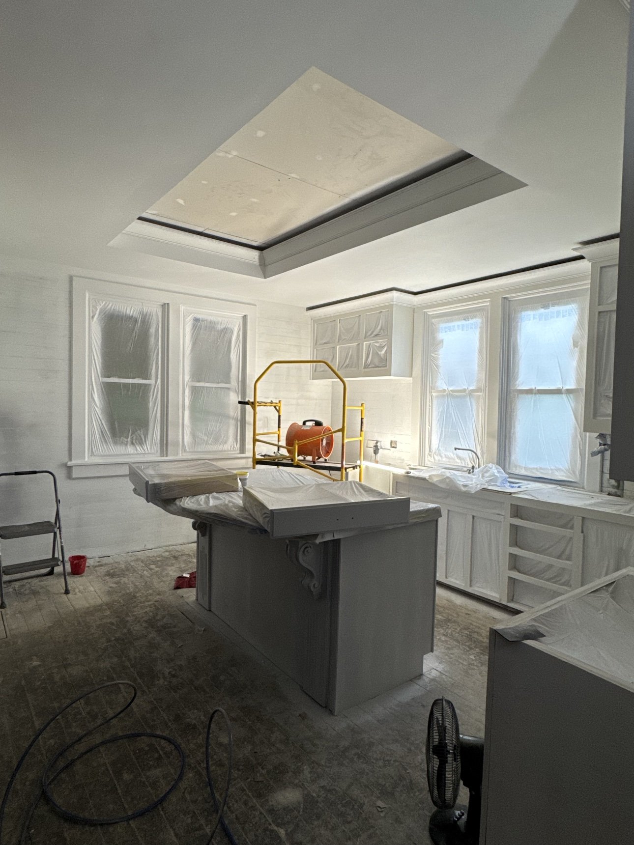 Kitchen renovation in progress — cabinetry primed and a tray ceiling under construction